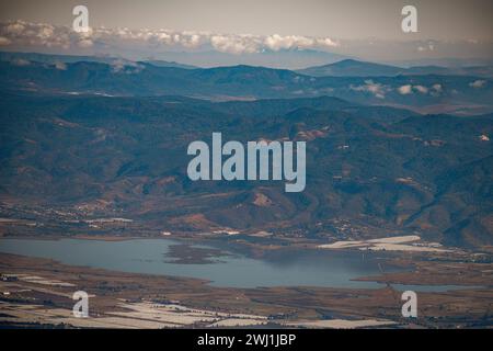 Una prospettiva aerea mozzafiato cattura le maestose montagne che circondano un tranquillo lago, con dolci colline nelle vicinanze Foto Stock