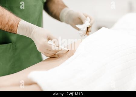 Primo piano delle mani di un medico estetico con una penna, marcando le aree di trattamento sulle gambe di una donna, mostrando una pianificazione medica precisa Foto Stock