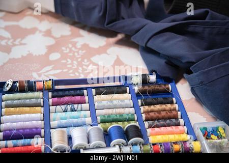 Rotoli di filettatura, bobine di filettatura in diversi colori per lavori di cucitura. Tavolo da lavoro con diversi utensili da cucire. Foto Stock