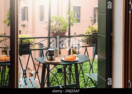 Moka, tazza di caffè, albicocche e bottiglia di vino bianco su un piccolo tavolo sul balcone Foto Stock