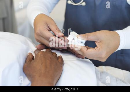 Mani di diverse donne medico e paziente anziano in camera d'ospedale Foto Stock