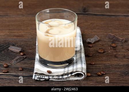 Bicchiere con ghiaccio in liquore originale irlandese, chicchi di caffè e pezzi di cioccolato. Sfondo in legno, spazio copie. Foto Stock