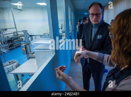 Schwerin, Germania. 12 febbraio 2024. Jochen Schulte, Segretario di Stato per gli affari economici del Meclemburgo-Vorpommern, si informa dell'assemblaggio di dispositivi medici per la liposuzione di fronte alla camera bianca di Human Med AG. La società con sede a Schwerin e l'Università e Centro medico Rostock stanno lavorando insieme su questo progetto. Il dispositivo utilizza vibrazioni o un getto d'acqua per aspirare il grasso dal corpo umano e viene utilizzato nel trattamento chirurgico del lipedema, un disturbo della distribuzione del grasso. Crediti: Jens Büttner/dpa/Alamy Live News Foto Stock