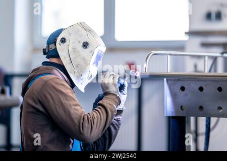 Un tecnico che indossa dispositivi di protezione individuale è un metallo per la saldatura Foto Stock