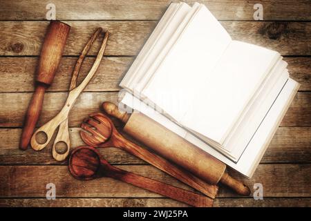 Vari utensili da cucina in legno e ricettario vintage sul tavolo Foto Stock