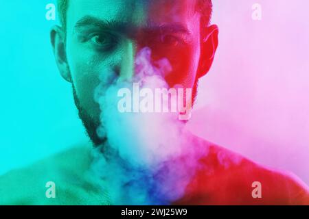 Bellissimo giovane con pelle bagnata in una sigaretta o marijuana colorata e leggera Foto Stock
