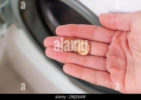 Monete trovate dal fusto di una lavatrice, lasciate in tasche per abiti da vicino in mano Foto Stock