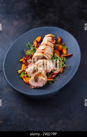 Filetto di maiale mangalica arrosto ripieno di noci tritate e zucca e avvolto in pancetta servito con verdure come vicino - Foto Stock