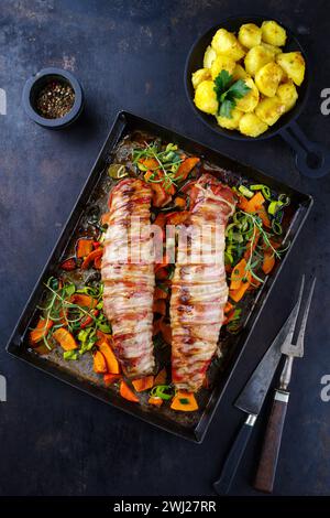 Filetto di maiale mangalica arrosto ripieno di noci tritate e zucca e avvolto in pancetta servito con verdure e bollito Foto Stock