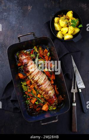 Filetto di maiale mangalica arrosto ripieno di noci tritate e zucca e avvolto in pancetta servito con verdure e bollito Foto Stock