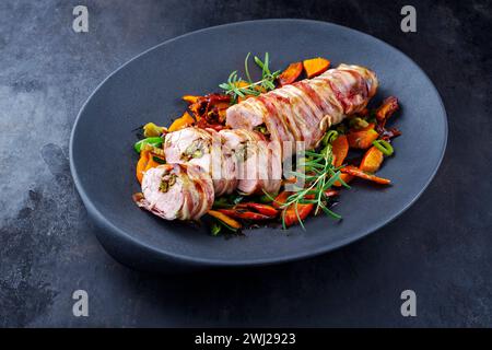 Filetto di maiale mangalica arrosto ripieno di noci tritate e zucca e avvolto in pancetta servito con verdure come vicino - Foto Stock