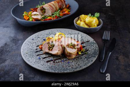 Filetto di maiale mangalica arrosto ripieno di noci tritate e zucca e avvolto in pancetta servito con verdure e bollito Foto Stock