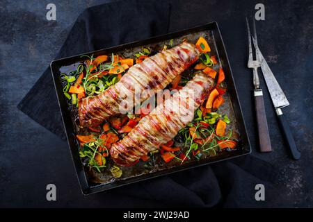 Filetto di maiale mangalica arrosto ripieno di noci tritate e zucca e avvolto in pancetta servito con verdure come parte superiore Foto Stock