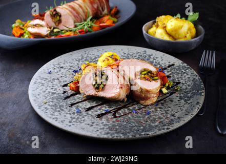 Filetto di maiale mangalica arrostito ripieno con noci tritate e zucca avvolta in pancetta e servito con verdure Foto Stock