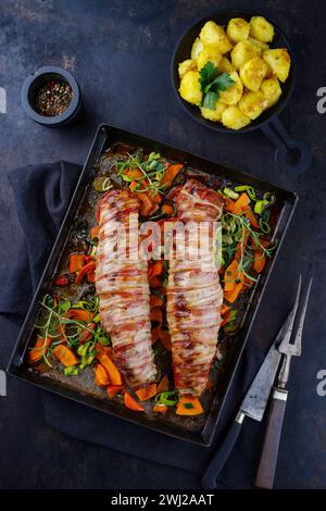 Filetto di maiale mangalica arrosto ripieno di noci tritate e zucca e avvolto in pancetta servito con verdure e bollito Foto Stock