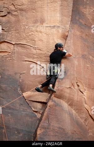 Uomo determinato che arrampica sulla scogliera rocciosa nel deserto Foto Stock