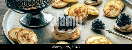 Blinis con panorama caviale nero. Mini pancake su un piatto festivo Foto Stock
