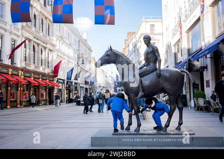 I bambini giocano sotto le gambe di una scultura intitolata "Horse and Rider", in Bond Street, il 12 febbraio 2024, a Londra, Inghilterra. 'Horse and Rider' è una scultura equestre in bronzo del 1974 di Elisabeth Frink. Il lavoro fu commissionato per un sito a Mayfair; un altro cast è a Winchester. Fu descritto da Frink come "un simbolo senza età di uomo e cavallo". Foto Stock