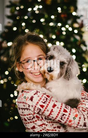 Tween ragazza in occhiali si accosta con il cucciolo di schnauzer a Natale Foto Stock