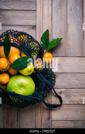 Set di agrumi in sacchetto di tessuto su un vecchio tavolo di legno. Concetto di cibo sano e zero rifiuti Foto Stock