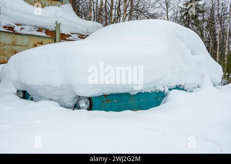 Auto sotto la neve. Molta neve dopo una nevicata. L'auto è completamente ricoperta di neve. Pericolo di nevicate per le auto. Problema di trasporto invernale. Co Foto Stock