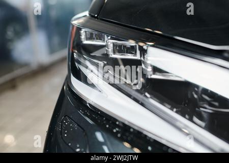 foto dell'oggetto di un'automobile moderna nera con i suoi fari in garage durante il servizio di pulizia Foto Stock