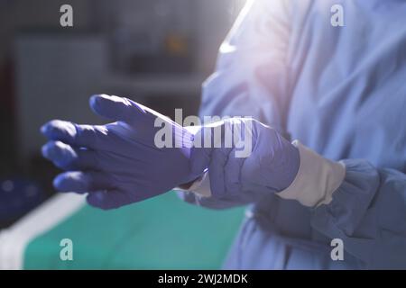 Intersezione del chirurgo birazziale femminile che indossa camice chirurgico e guanti medici in sala operatoria Foto Stock