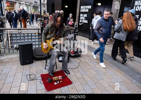 Uomo che suona una chitarra elettrica con pedali ad effetti al Circo di Oxford Street il 4 febbraio 2024 a Londra, Regno Unito. Al contrario del busking, questo musicista veniva filmato suonando nello stesso posto e eseguendo la stessa canzone che aveva fatto 7 anni fa. Una performance virtuosa dei Sultans of Swing della band dire Straights, incluso il famoso assolo di chitarra. Foto Stock