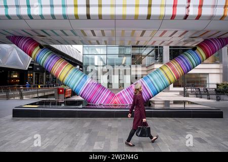 Persone che interagiscono con l’opera d’arte pubblica geometrica «Click Your Heels Together Three Times» dell’artista Adam Nathaniel Furman all’esterno del passaggio pedonale del tunnel presso Adams Plaza Bridge che collega North Collonade con Crossrail Place nel cuore del distretto finanziario di Canary Wharf il 6 febbraio 2024 a Londra, Regno Unito. Canary Wharf è un'area situata vicino all'Isola dei cani nel London Borough of Tower Hamlets ed è definita dalla Greater London Authority come parte del quartiere finanziario centrale di Londra. Foto Stock