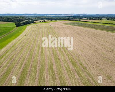 Agricoltura nel Regno Unito. Fotografia aerea con drone di John Deere, trattore, fienagione nell'Hampshire Foto Stock