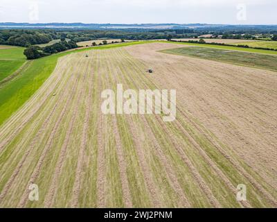 Agricoltura nel Regno Unito. Fotografia aerea con drone di John Deere, trattore, fienagione nell'Hampshire Foto Stock