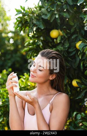 Ritratto di una bella donna con una bottiglia bianca di prodotto cosmetico Foto Stock