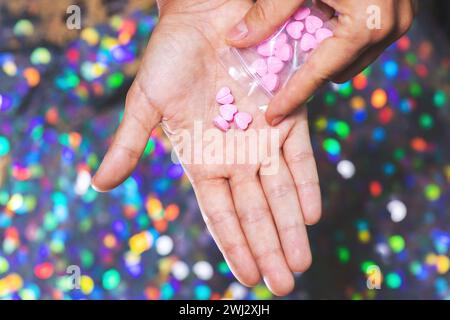 Uomo che versa pillole a forma di cuore sul palmo dal sacchetto con chiusura a cerniera. Foto Stock