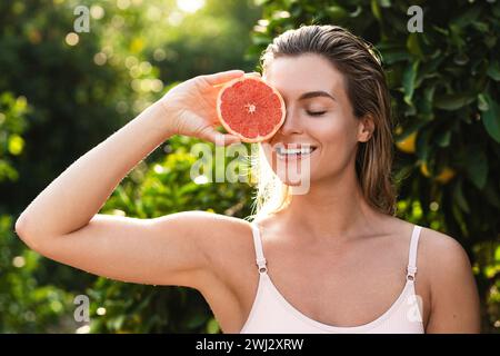 Bella donna con pelle liscia e pompelmo in mano Foto Stock