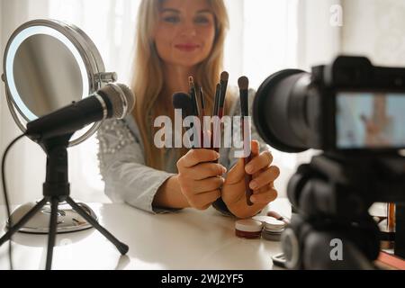 Beauty blogger che fa una recensione video di diversi pennelli per il trucco per i suoi follower Foto Stock