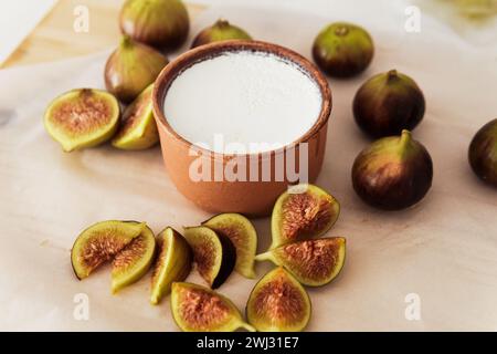 Delizioso yogurt greco naturale in un recipiente di argilla con fichi Foto Stock