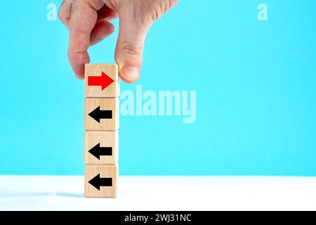 La mano. Cubi di legno con frecce. Superare la crisi dei problemi e il concetto di strada per il successo. invertire la direzione, alternare il concetto di direzione Foto Stock