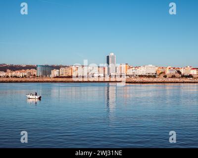 Figueira da Foz, Portogallo - 20 gennaio 2024: Vista frontale del centro città con una piccola barca da pesca galleggiante sul fiume Mondego Foto Stock