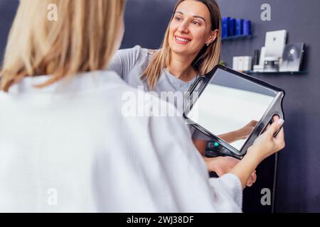 Medico che controlla la pelle della faccia della donna nella clinica di cosmetologia prima dell'ambulatorio di plastica Foto Stock