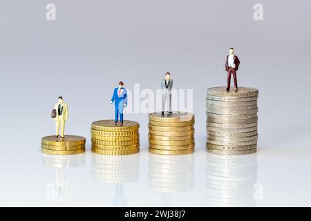 Persone giocattolo in piedi su una pila di monete in euro. simbolo della figurina per aumentare o ridurre il valore Foto Stock