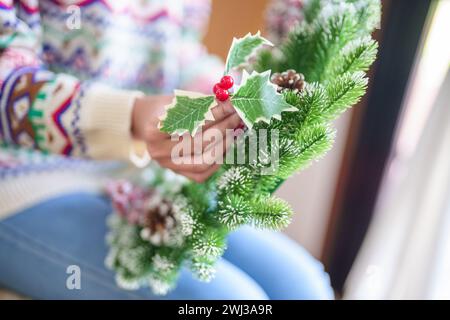 Donna che produce ghirlande di vigna decorazione di ghirlanda di Natale con fiori di verde invernale fatti a mano che creano wrea di Natale Foto Stock