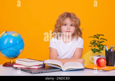 Allievo nerd della scuola elementare con libro isolato su sfondo giallo studio. Intelligenza geniale intelligente capretto pronto per imparare. Ritorno a scuola. Foto Stock