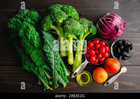 Insalata di arancia e cavolo sangue su una tavola di legno rustico: Lacinato kale, broccoli, pomodori d'uva e altri ingredienti per un'insalata sana Foto Stock