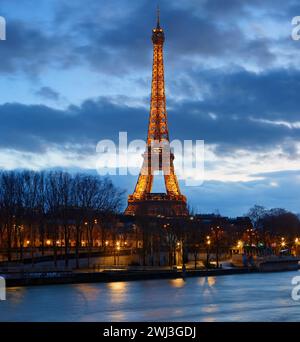 Parigi, Francia - 11 novembre 2023 : la vista notturna della Torre Eiffel, famoso monumento che si illumina al crepuscolo situato al confine della Senna. Foto Stock