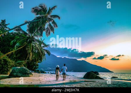 Isole tropicali delle Seychelles, Praslins Island Seychelles con coppie a piedi sulla spiaggia tropicale con palme Foto Stock