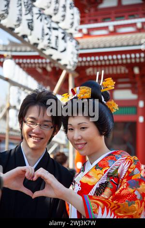 Una coppia asiatica posa per le fotografie al Tempio Sensoji di Asakusa, Tokyo, Giappone. Entrambi sono vestiti in costume tradizionale giapponese. Foto Stock