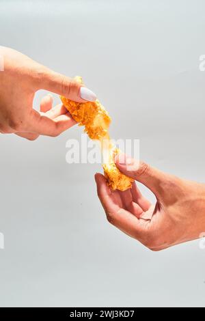 I bastoncini di mozzarella impanata e croccanti di formaggio si allungano a due mani Foto Stock