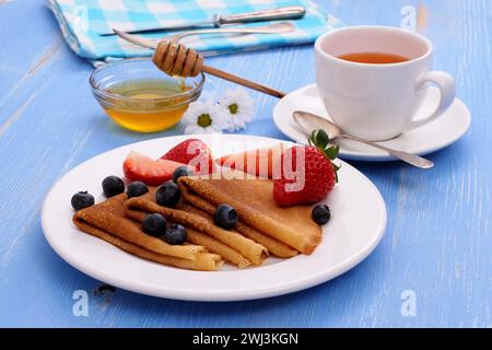 Frittelle con fragole, mirtilli e miele freschi Foto Stock