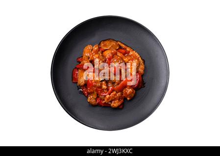 Deliziosa carne succosa con peperoni caldi e salsa su un piatto di ceramica nera Foto Stock