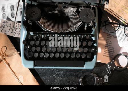 Macchina da scrivere retrò, manette e file criminali su un tavolo scuro Foto Stock